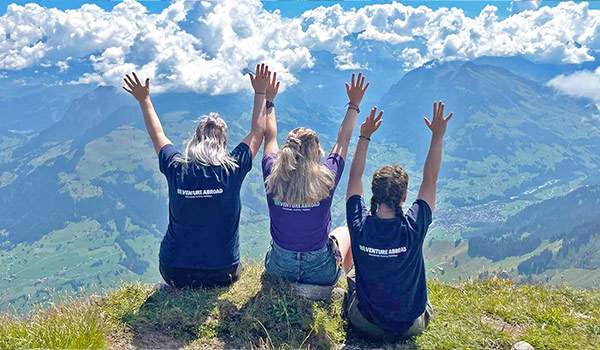 Tour reps with hands in the air on a swiss mountain top
