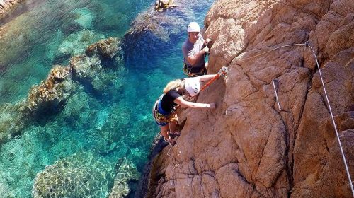 Two people rock climbing by the sea